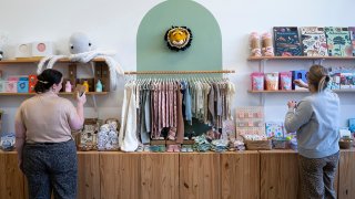 Elizabeth Mahon, right, owner of the baby store Three Littles, and sales associate Charlotte Santoli search through inventory for "Made in China" stickers at the Union Market location in Washington, on Wednesday, April 16, 2025.