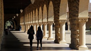 Students walk on the Stanford University campus in Stanford, Calif.