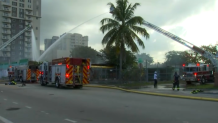Crews work to extinguish a fire at a vacant lumber warehouse in Miami on May 30, 2025.
