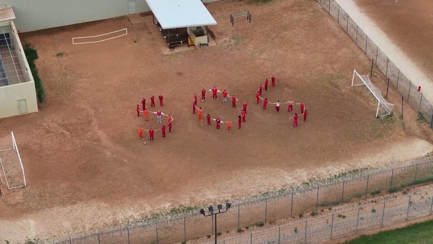 Migrants at a detention center form a human SOS