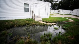 FILE &#8211; Fetid water pools outside a mobile home in a small mobile home park in rural Hayneville, Ala., Lowndes County, Aug. 1, 2022.