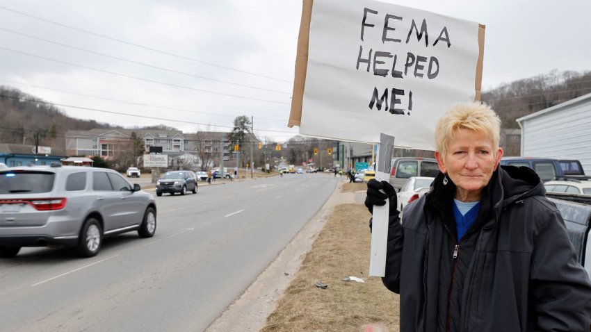 Swannanoa resident Lucy Bickers, who received assistance from FEMA after Hurricane Helene damaged her property, holds a sign in support of the government disaster agency as she waits on the route of visiting U.S. President Donald Trump’s motorcade in Swannanoa, North Carolina, U.S., January 24, 2025. 