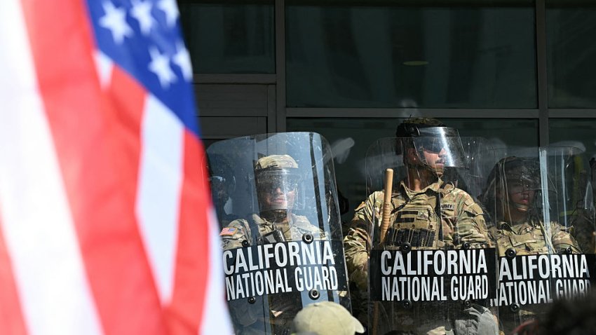 A demonstrator holds an upside down US flag as they face California National Guard  standing guard outside the Federal Building during a protest in response to federal immigration operations in Los Angeles, on June 9, 2025. US President Donald Trump on June 9 ordered active-duty Marines into Los Angeles, vowing those protesting immigration arrests would be “hit harder” than ever. Protests in Los Angeles, home to a large Latino population, broke out on June 6, triggered by immigration raids that resulted in dozens of arrests of what authorities say are illegal migrants and gang . (Photo by RONALDO SCHEMIDT / AFP) (Photo by RONALDO SCHEMIDT/AFP via Getty Images)