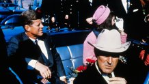 US President John F Kennedy (left), First Lady Jacqueline Kennedy (in pink), and Texas Governor John Connally ride in a motorcade from the Dallas airport into the city.