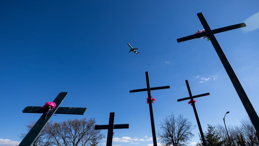 An airplane takes off from Reagan National Airport beyond a memorial for the victims of the midair collision between an American Airlines plane and a military helicopter over the Potomac River, on Feb. 1, 2025 in Arlington, Virginia. (Photo by Al Drago/Getty Images)