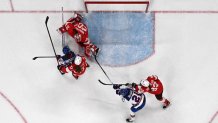 Team USA forwards Joy Dunne and Alex Carpenter try to score against Switzerland's Andrea Braendli during the women's preliminary round Group A Ice Hockey match.