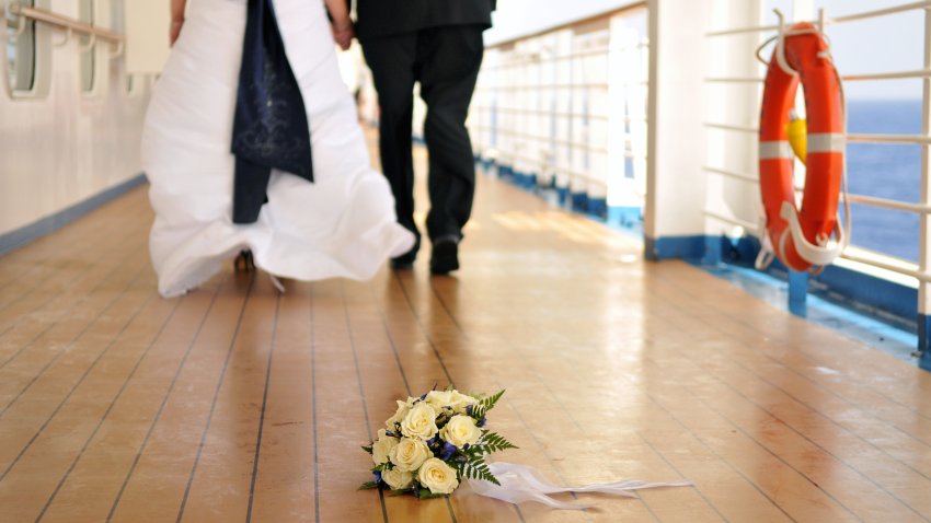 Wedding couple walking in the distance with bouquet in front on a deck of a cruise ship