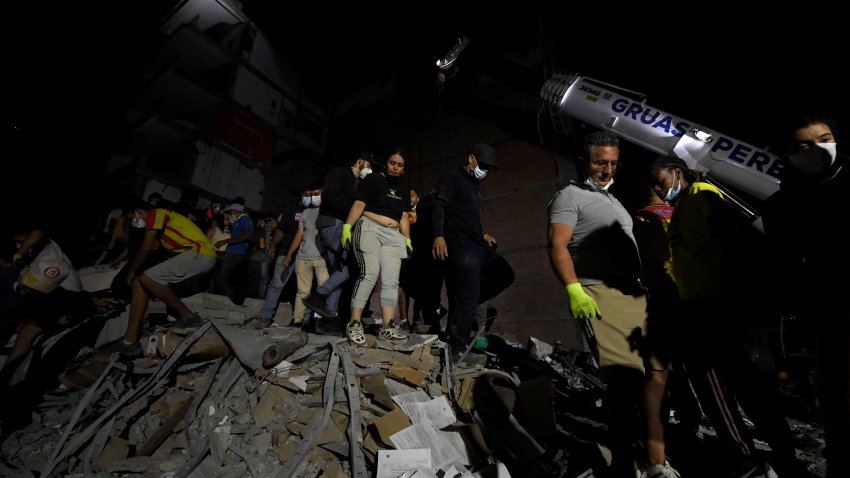 Rescuers and locals clear the rubble and look for survivors at a collapsed building after an earthquake in Pereira, Colombia on August 10, 2026. A magnitude 7.4 earthquake struck Colombia on August 10, 2026, and killed at least 111 people, damaged more than 1,500 buildings, and left an unknown number of people buried under rubble. The government declared a state of emergency to attend to the quake that shook several cities across the coffee-producing region, the Pacific coast, and neighboring Latin American countries, sending terrified residents racing into the street. (Photo by Jaime SALDARRIAGA / AFP via Getty Images)