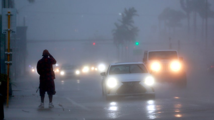 A man waits for a bus in the pouring rain at an uncovered bus stop on Federal Highway in Fort Lauderdale, Florida, on Dec. 16, 2023. (Mike Stocker/South Florida Sun Sentinel/Tribune News Service via Getty Images)